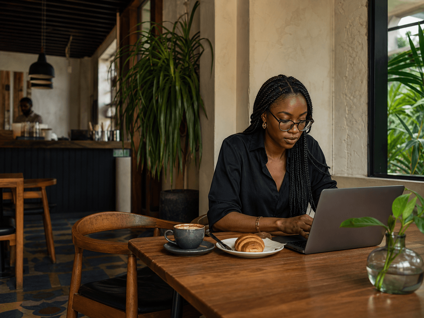 A woman working from a warm, plant-filled cafe in Lagos